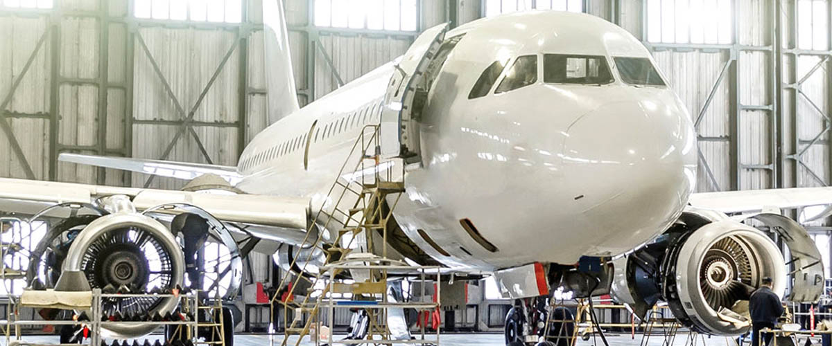 An airplane being built for the aerospace and aviation industry. Information panels (could be used for all if necessary): A young professional in the aerospace and aviation industry working on the wing of a plane.