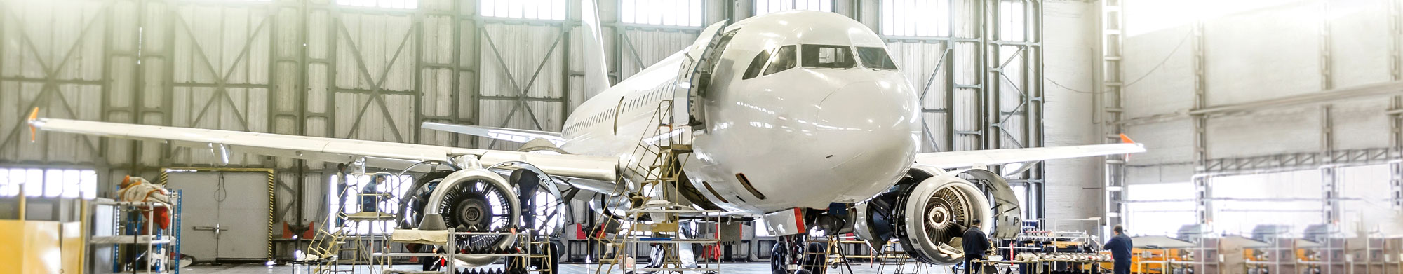 An airplane being built for the aerospace and aviation industry. Information panels (could be used for all if necessary): A young professional in the aerospace and aviation industry working on the wing of a plane.