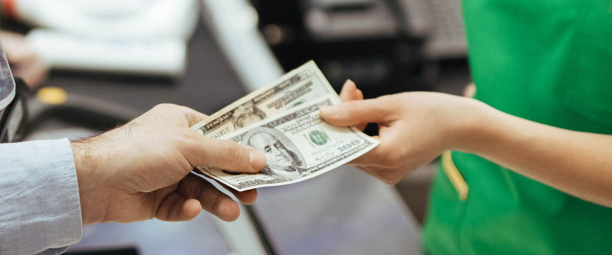 A customer at a grocery store hands an employee money for his purchase.