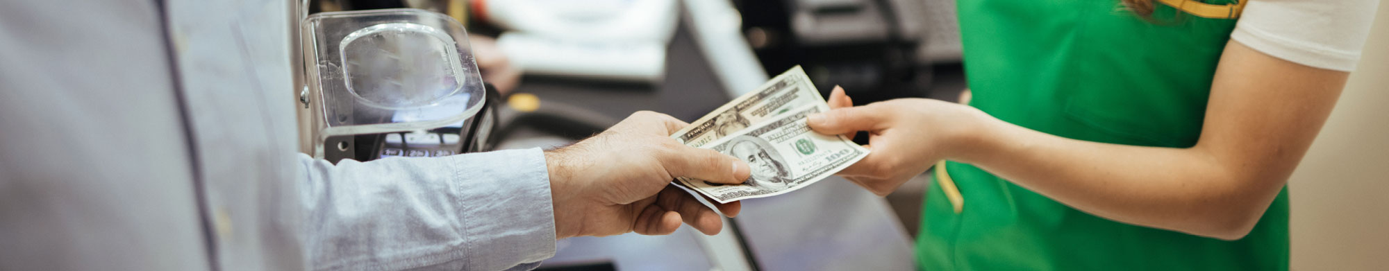 A customer at a grocery store hands an employee money for his purchase.