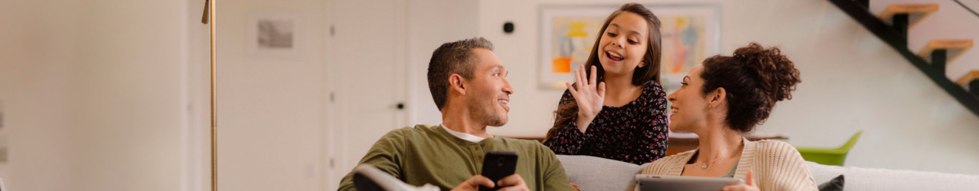 A mother, father and young daughter who reside in Arizona chatting in their home.