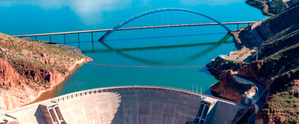 An aerial view of Theodore Roosevelt Dam and the Roosevelt Lake Bridge spanning Roosevelt Lake.