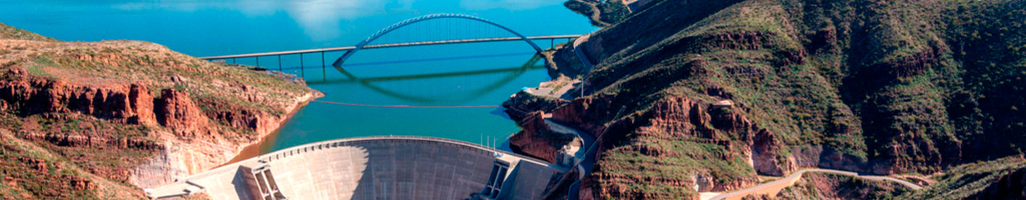 An aerial view of Theodore Roosevelt Dam and the Roosevelt Lake Bridge spanning Roosevelt Lake.