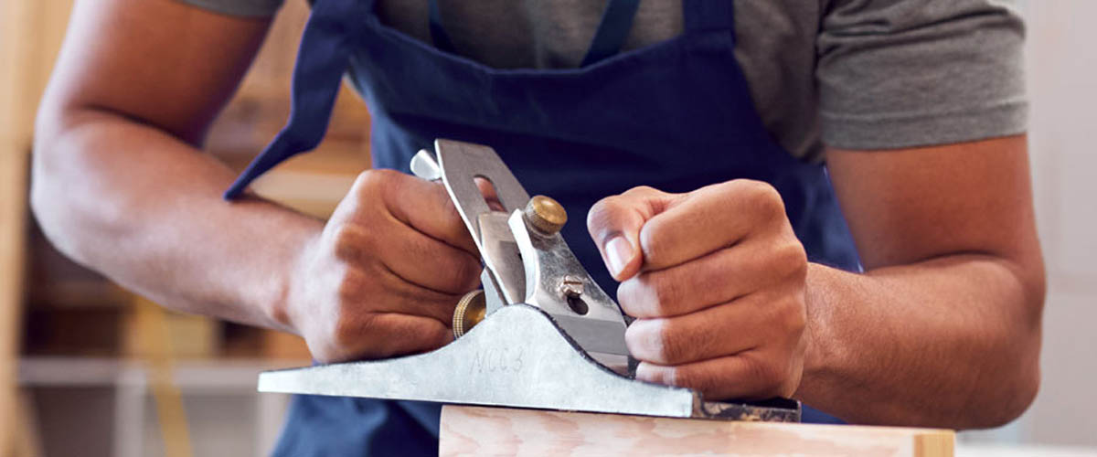  A craftsman uses a hand plane to shape a piece of wood.