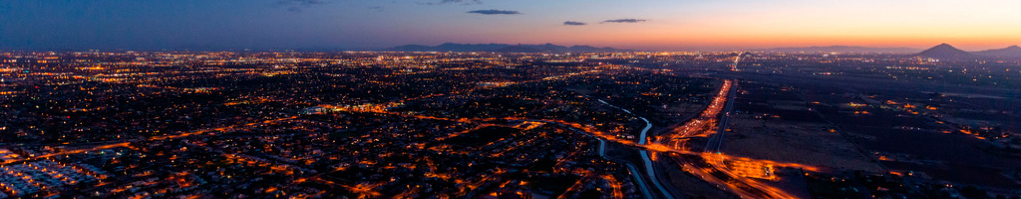 Aerial image of Phoenix at night, with a view of the freeways and roads lit up in the dark.