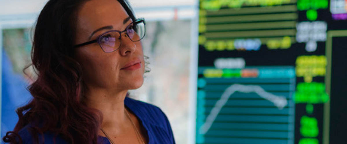 A woman looks on dutifully at her screens filled with colorful charts. She is part of Arizona's talented labor pool.